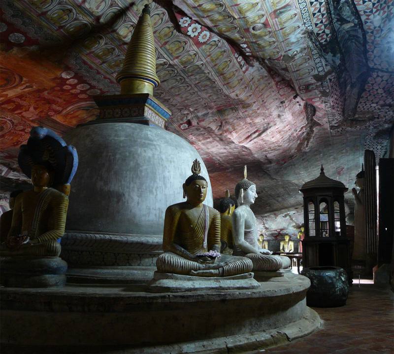 Stupa ringed by seated Buddha statues beneath painted rock ceilings, Dambulla Cave Temple, Sri Lanka