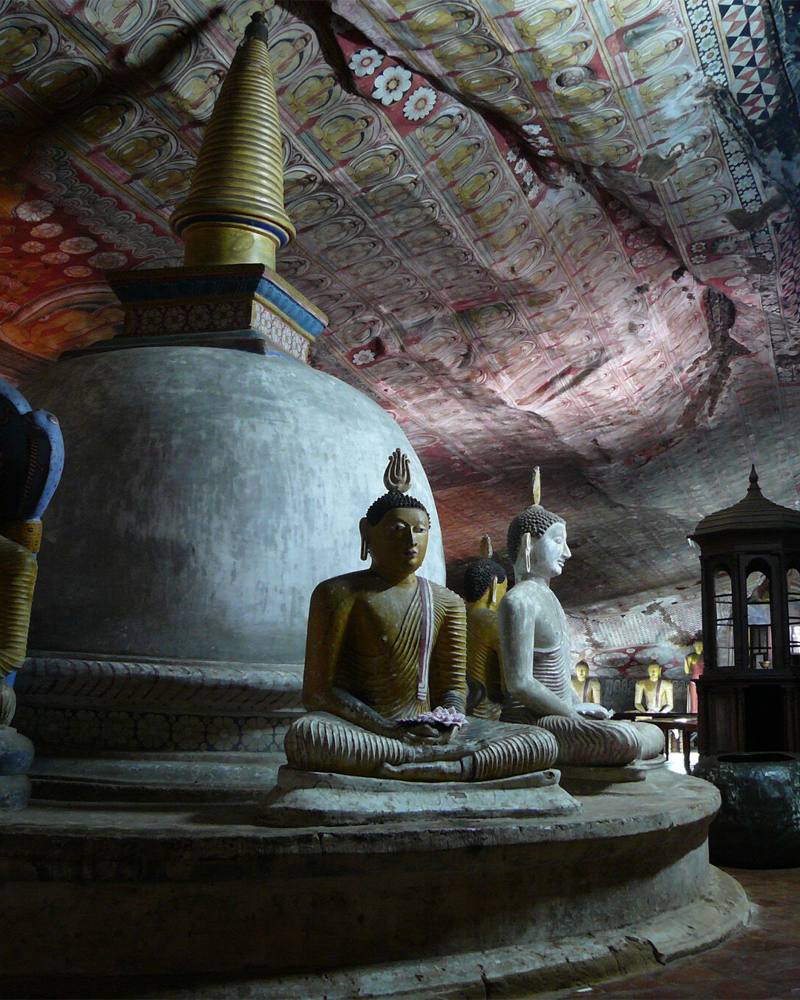Stupa ringed by seated Buddha statues beneath painted rock ceilings, Dambulla Cave Temple, Sri Lanka
