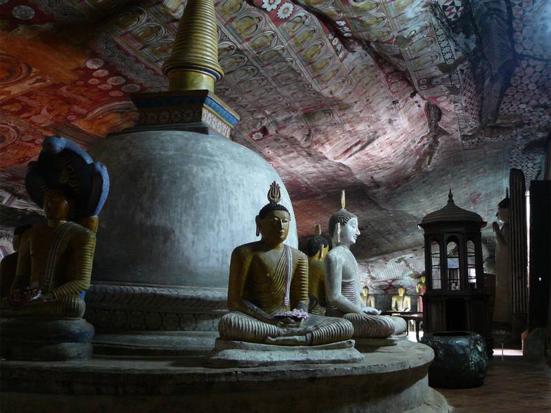 Stupa ringed by seated Buddha statues beneath painted rock ceilings, Dambulla Cave Temple, Sri Lanka