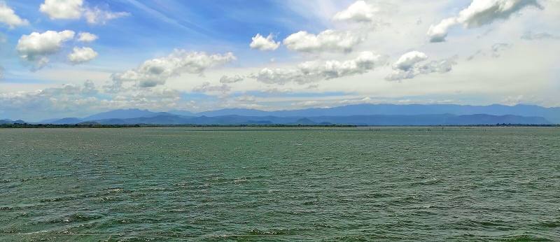Udawalawe reservoir stretching to distant mountains under a cloud-dotted sky, Sri Lanka