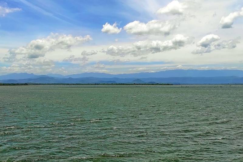 Udawalawe reservoir stretching to distant mountains under a cloud-dotted sky, Sri Lanka