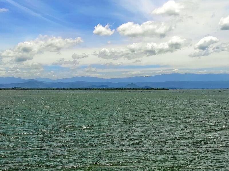 Udawalawe reservoir stretching to distant mountains under a cloud-dotted sky, Sri Lanka